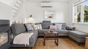 A modern living room with a sectional sofa, a fireplace, and a large window with a view of greenery. - "Anemette" - 100m from the sea by Interhome (Nexø)