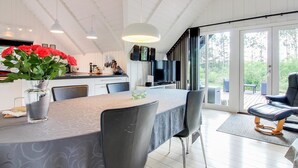 Una cucina moderna con zona pranzo, ampie finestre e una porta scorrevole in vetro che dà su un patio esterno.