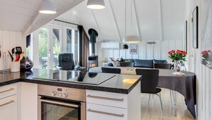 Una cucina moderna con forno a incasso, una zona pranzo con tavolo e sedie, e un angolo relax con divano e camino.