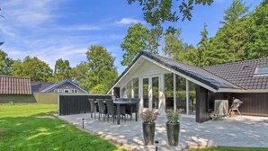 A patio with a dining table and chairs, surrounded by a grassy area and a wooden fence. - "Arnsten" by Interhome (Ansager)