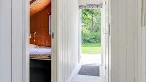 A narrow hallway with a wooden ceiling and a bed in a room to the left. - "Arnsten" by Interhome (Ansager)