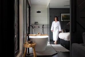Un baño moderno con una bañera independiente, un taburete de madera y un diseño minimalista.