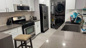 A modern kitchen with white cabinets, stainless steel appliances, a granite countertop, and a built-in oven.