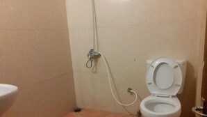 A small bathroom with a toilet, a sink, and a shower. - Cool Land Hot Hut (Nuwara Eliya)