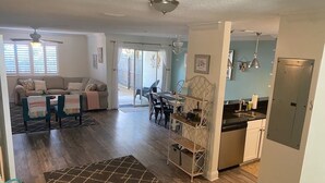 Un amplio espacio de sala con un sofá, sillas, una mesa de comedor y una zona de cocina con un fregadero y armarios.