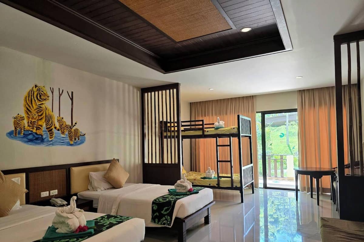 Une chambre d’hôtel avec deux lits, une fresque représentant des tigres, un balcon et une vue sur la verdure.