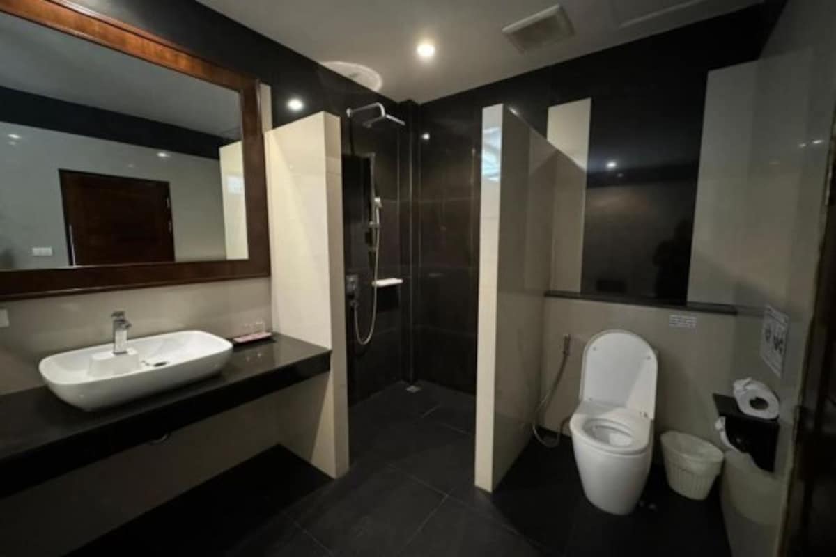 Une salle de bain moderne avec un grand miroir, un lavabo, une douche et des toilettes.
