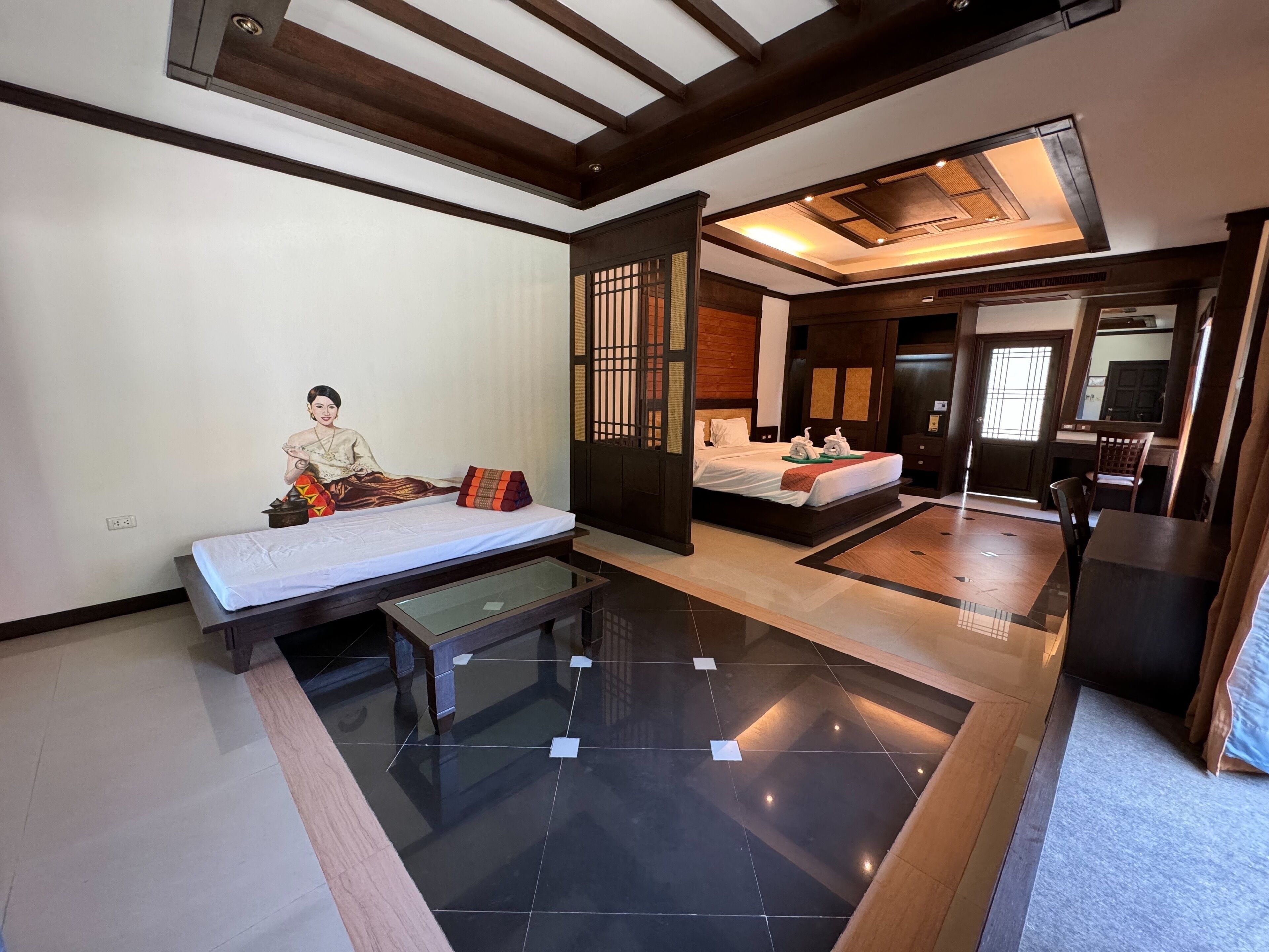 A modern hotel room with a large bed, a separate seating area, and a dining table.