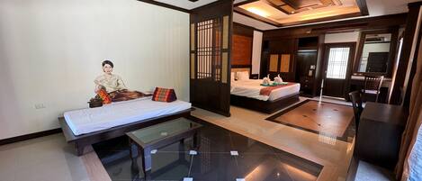 A modern hotel room with a large bed, a separate seating area, and a dining table.