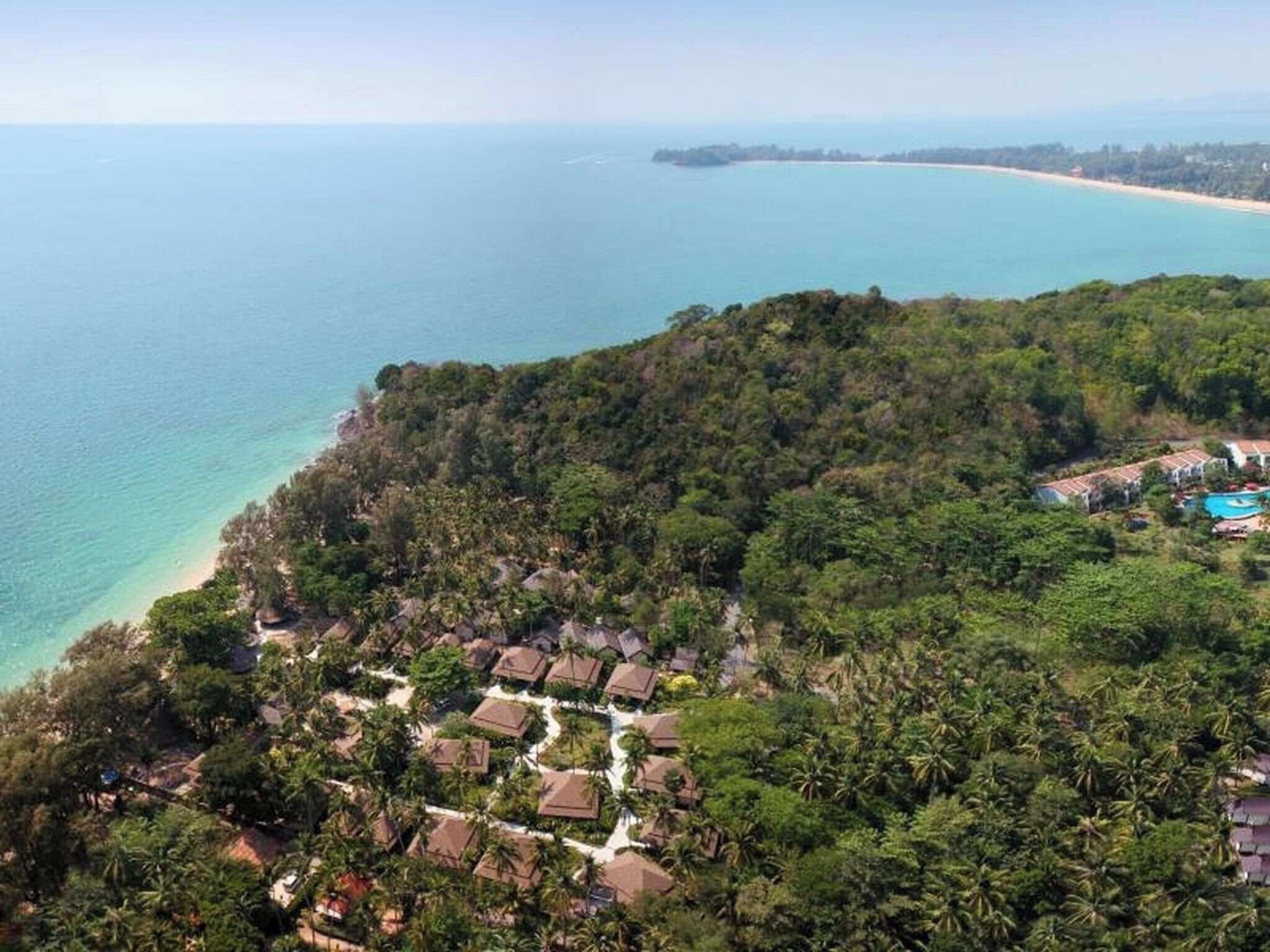 Un resort con varias cabañas, una piscina y vistas a la costa.