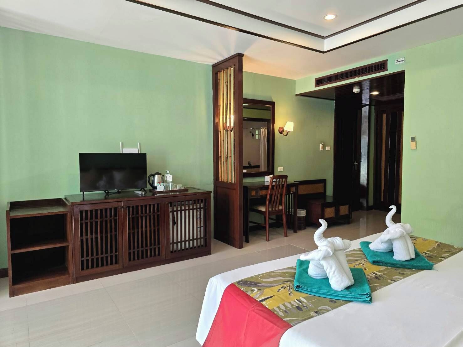 A hotel room with a TV, a desk, a chair, and two beds with towels.