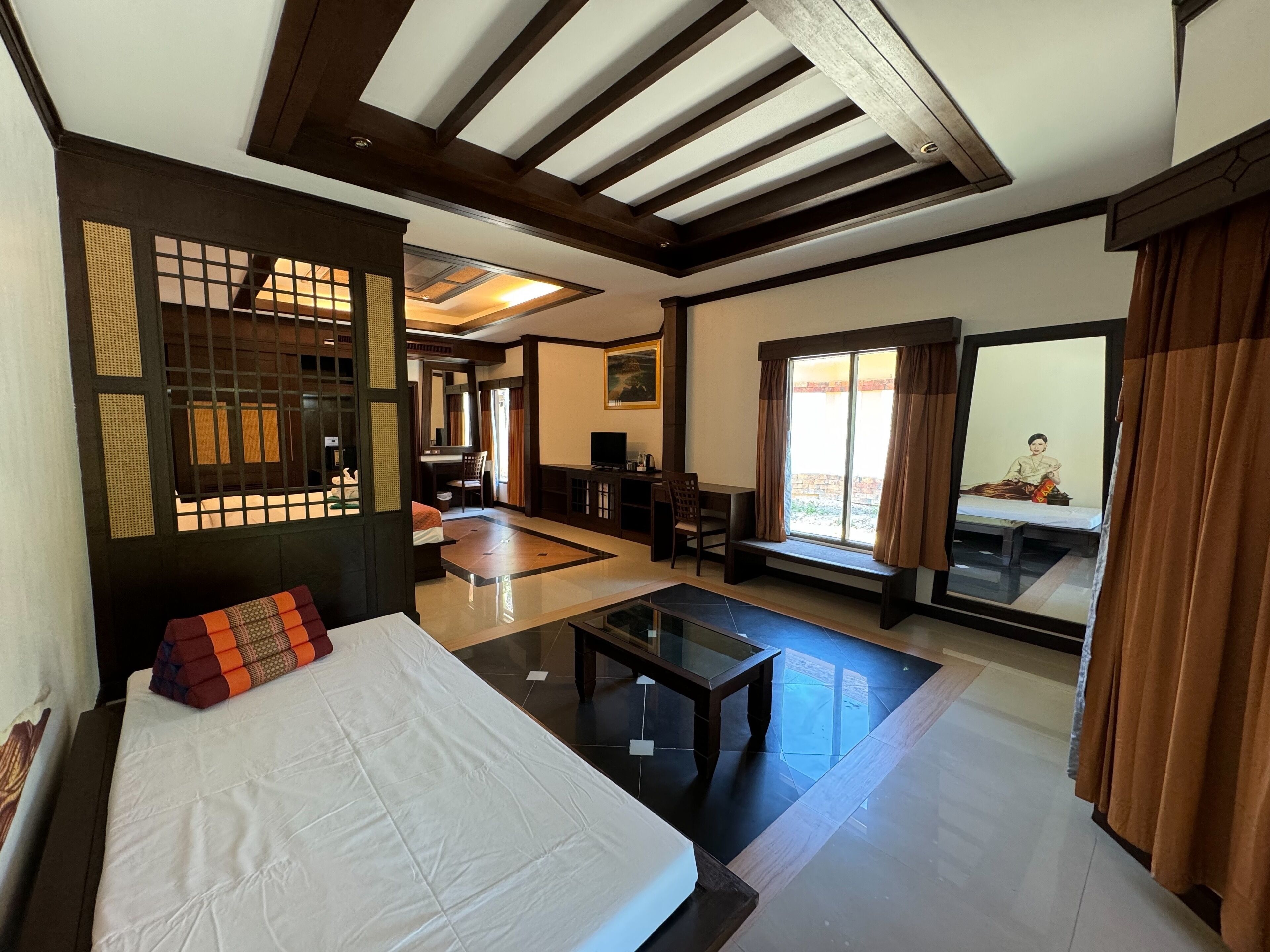 Une chambre d’hôtel comprenant un lit, un bureau, une chaise, un canapé, une table basse et une grande fenêtre avec des rideaux.