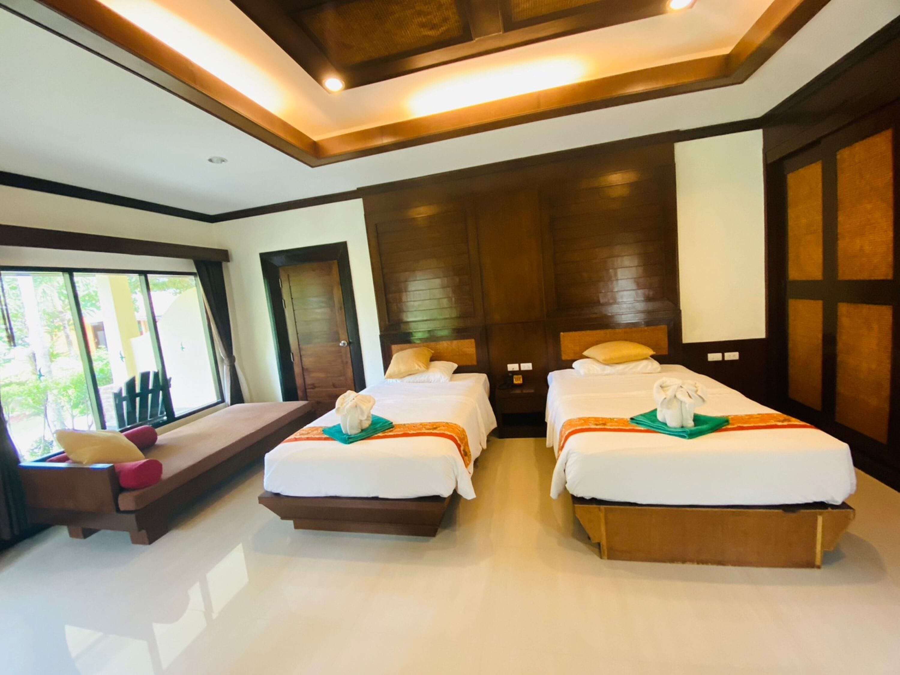 Habitación de hotel con dos camas, un banco y un ventanal grande.