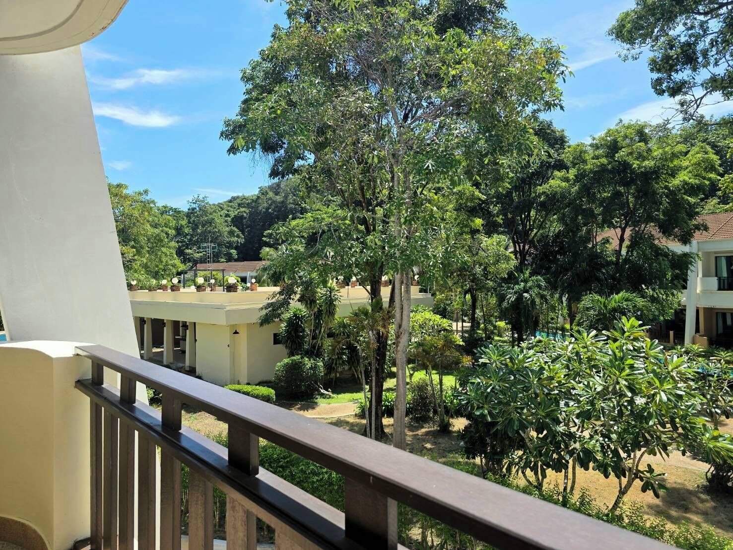 A balcony with a view of a courtyard surrounded by trees and buildings.