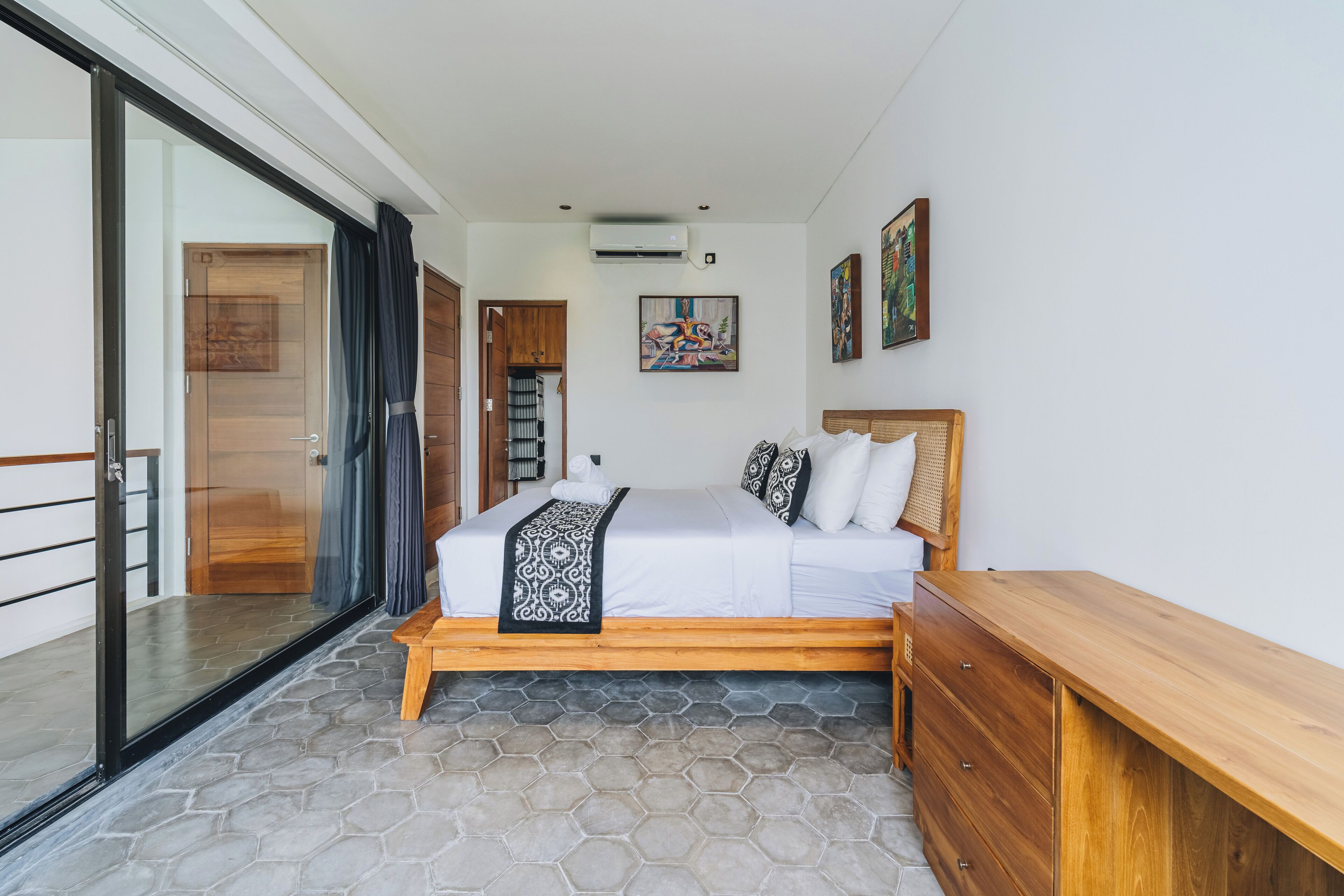 Een slaapkamer met een bed, nachtkastje van hout en een kledingkast.