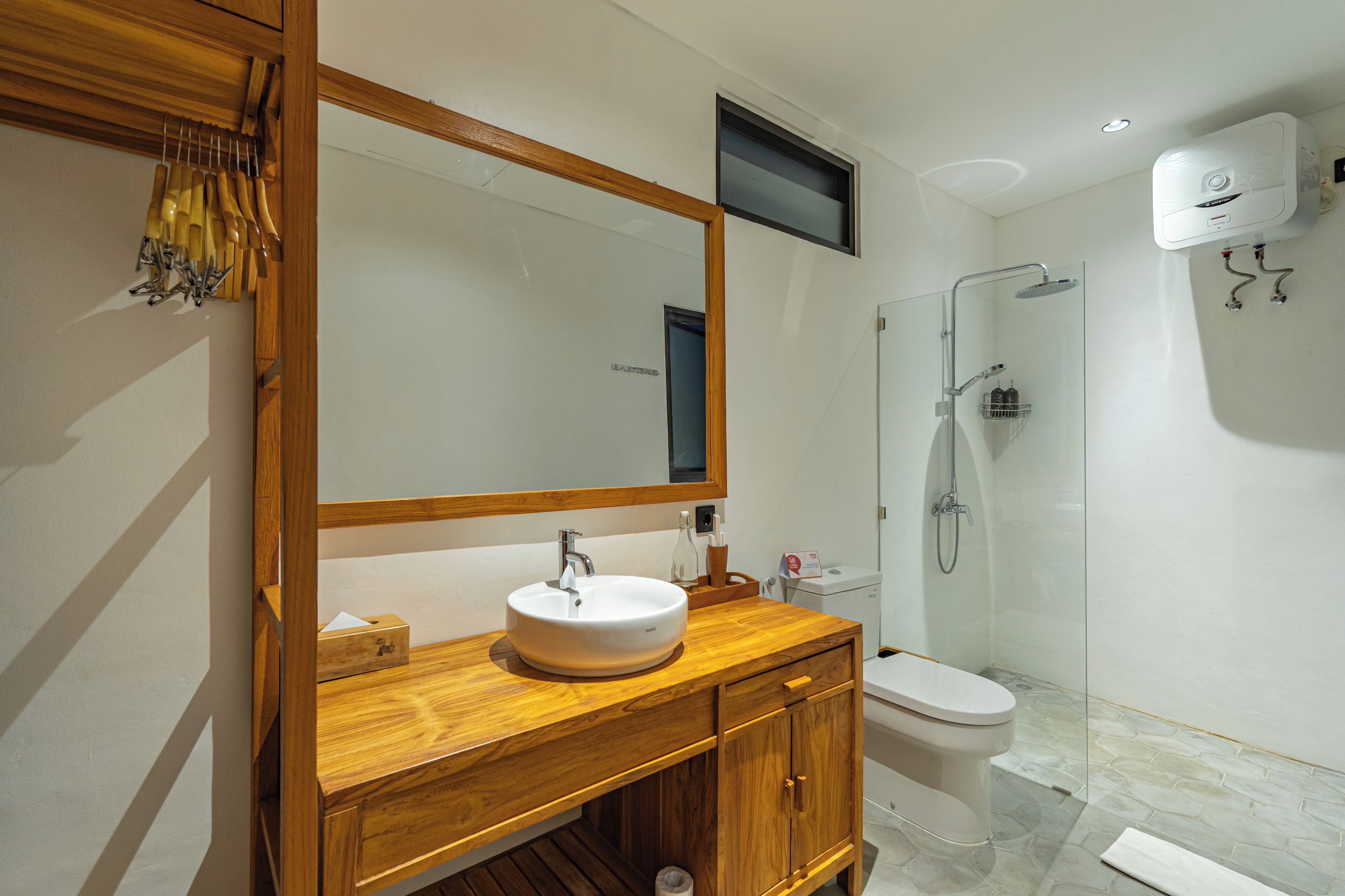 A modern bathroom with a wooden vanity, a round sink, a toilet, and a glass-enclosed shower.