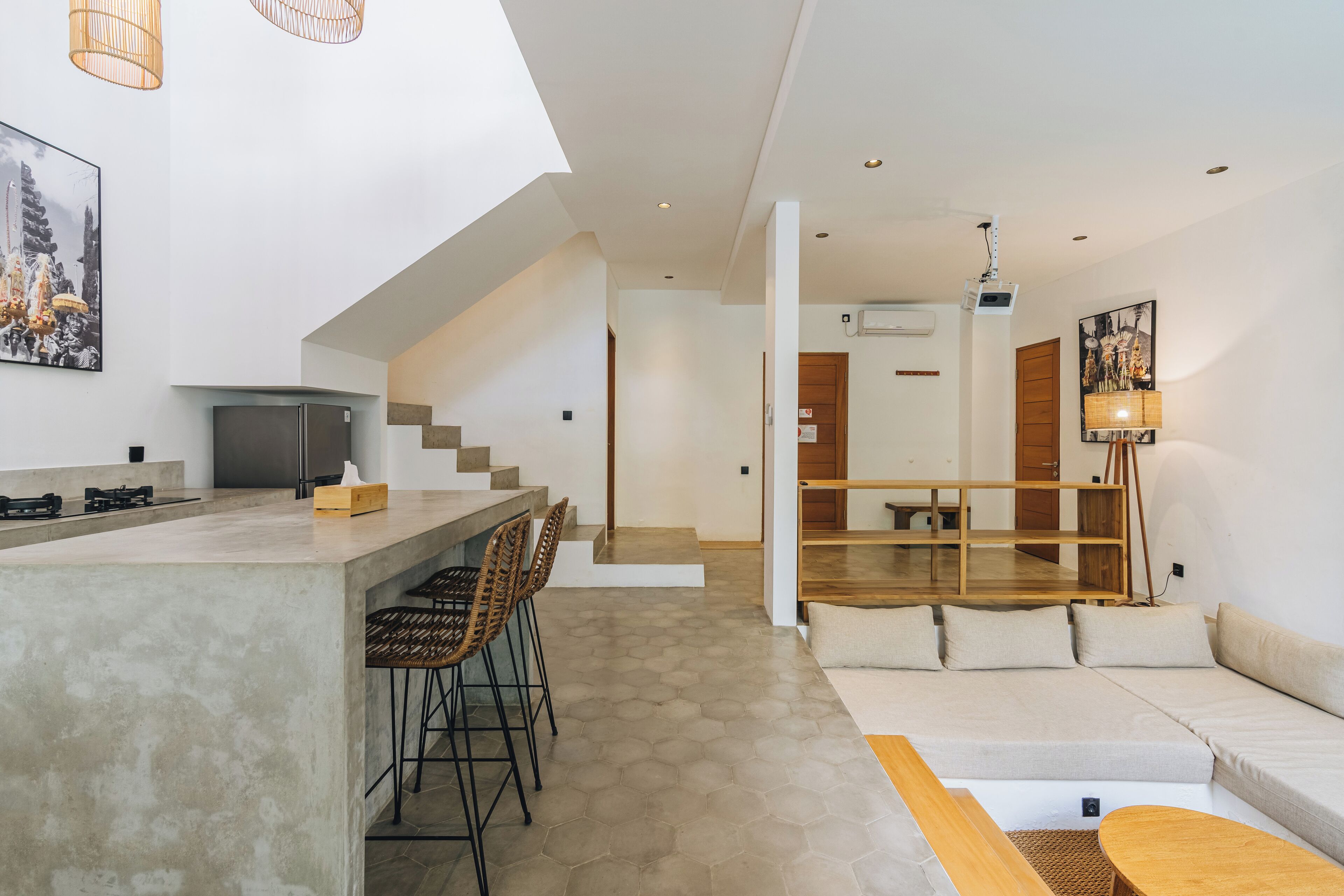 A modern kitchen with a bar area, a dining space with a sofa, and a staircase leading to another level.