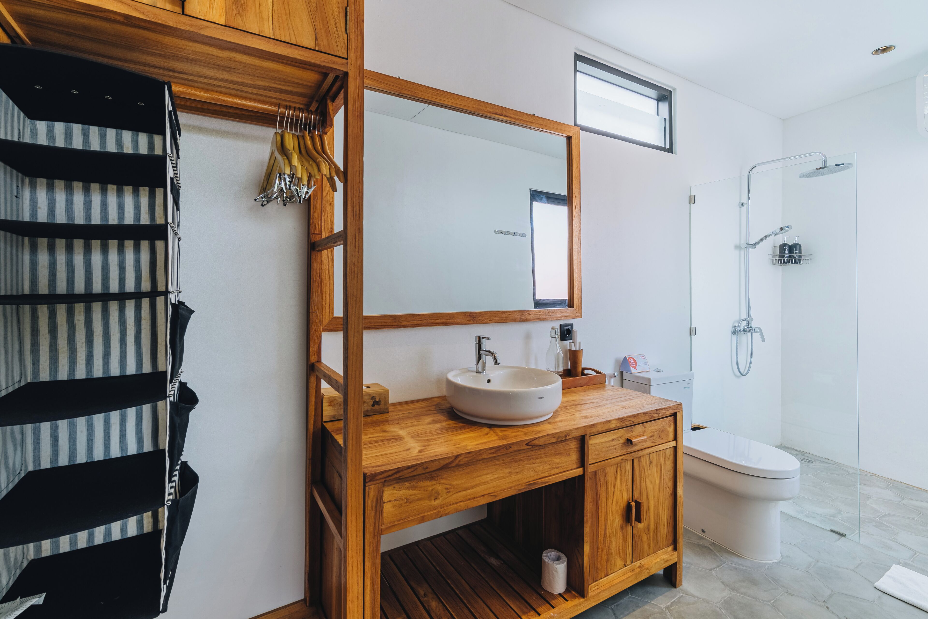 A modern bathroom with a wooden vanity, a large mirror, a toilet, and a shower.