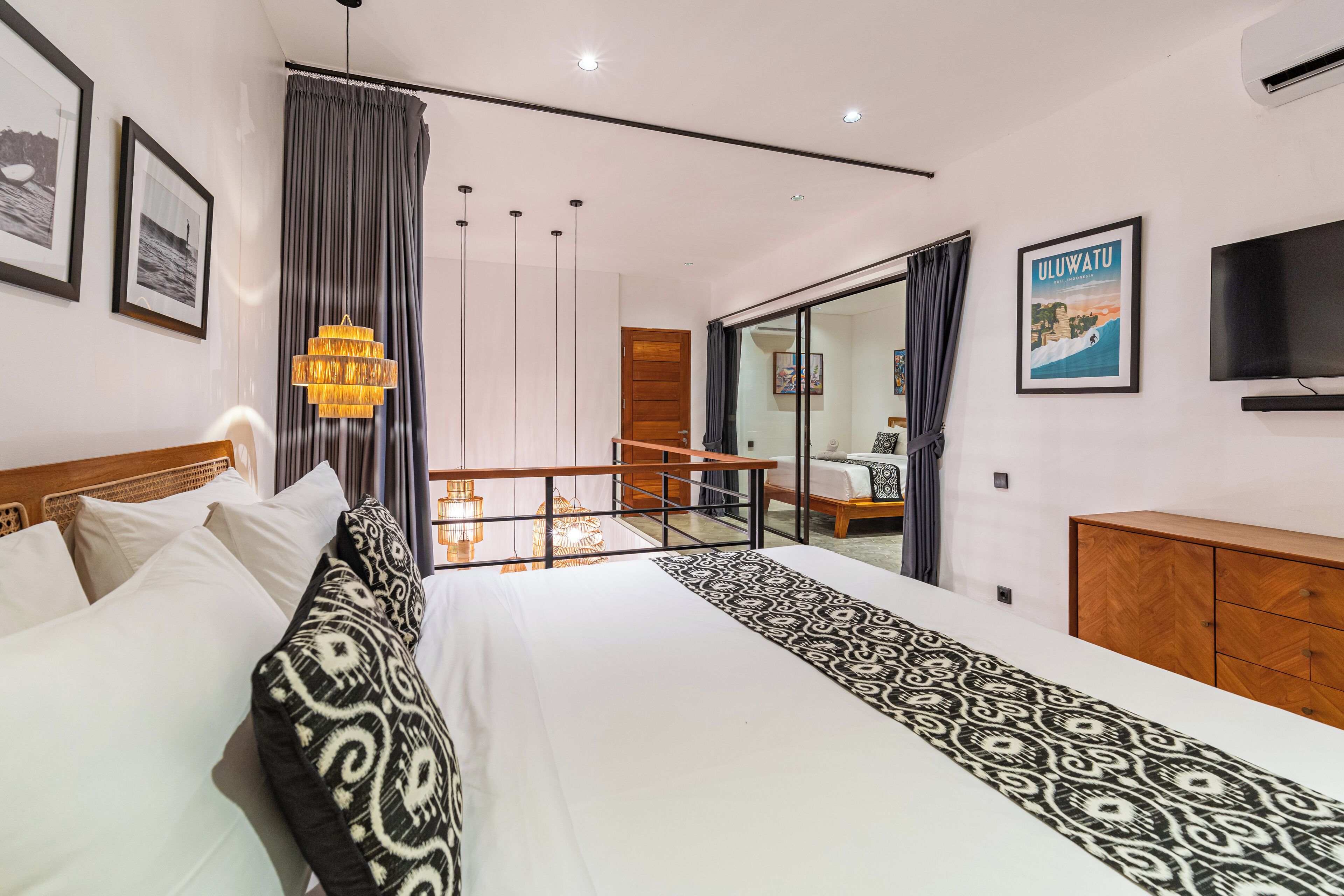 A modern hotel room with a large bed, a chandelier, a TV, and a balcony with a view.