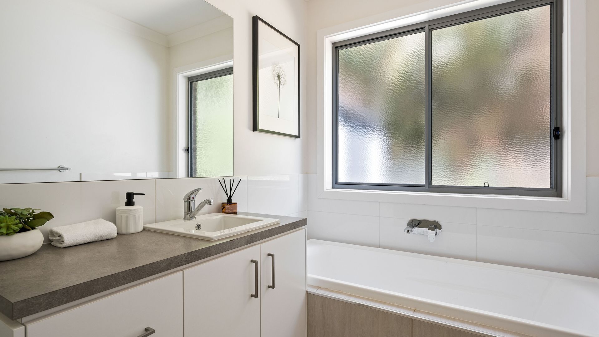 Ein modernes Badezimmer mit großem Spiegel, Waschbecken und Badewanne.