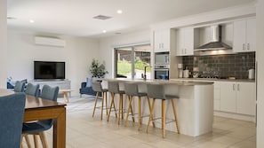 Enjoy meals in the central island kitchen with an oven and range hood, adjacent to a dining area and comfortable seating space.