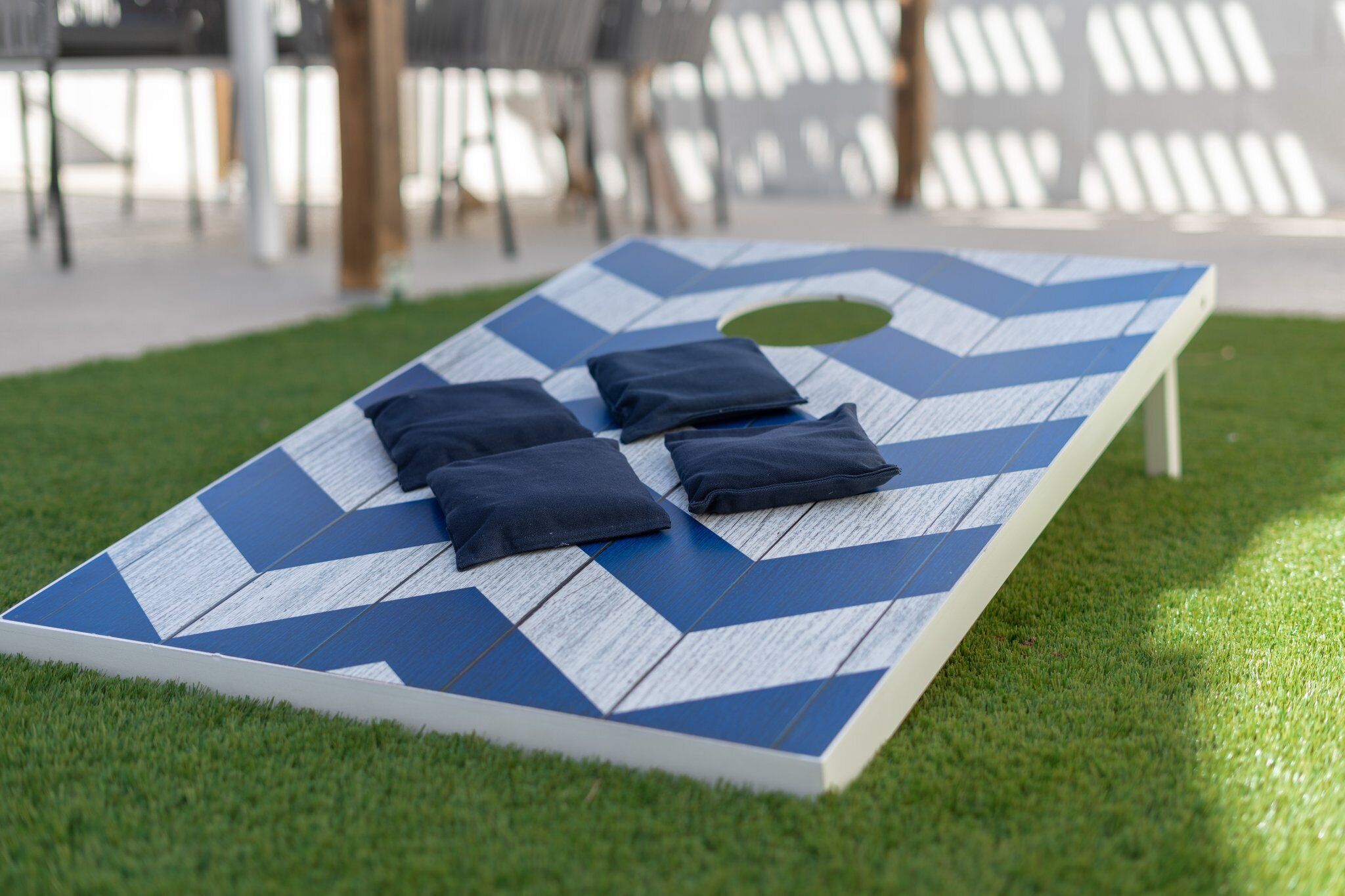 A blue and white chevron-patterned board game on a grassy lawn.