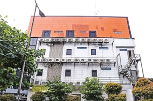 Ein mehrstöckiges Gebäude mit rotem Dach, mehreren Klimaanlagen und einem sichtbaren Brandschutztreppenhaus.