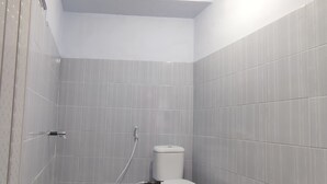 A small, modern bathroom with a toilet and shower area, tiled walls, and a ceiling light. - Hotel O Khazanah Room Syariah (Yogyakarta)