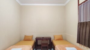 A small, clean room with two single beds, a small table, and a chair. - Hotel O Khazanah Room Syariah (Yogyakarta)