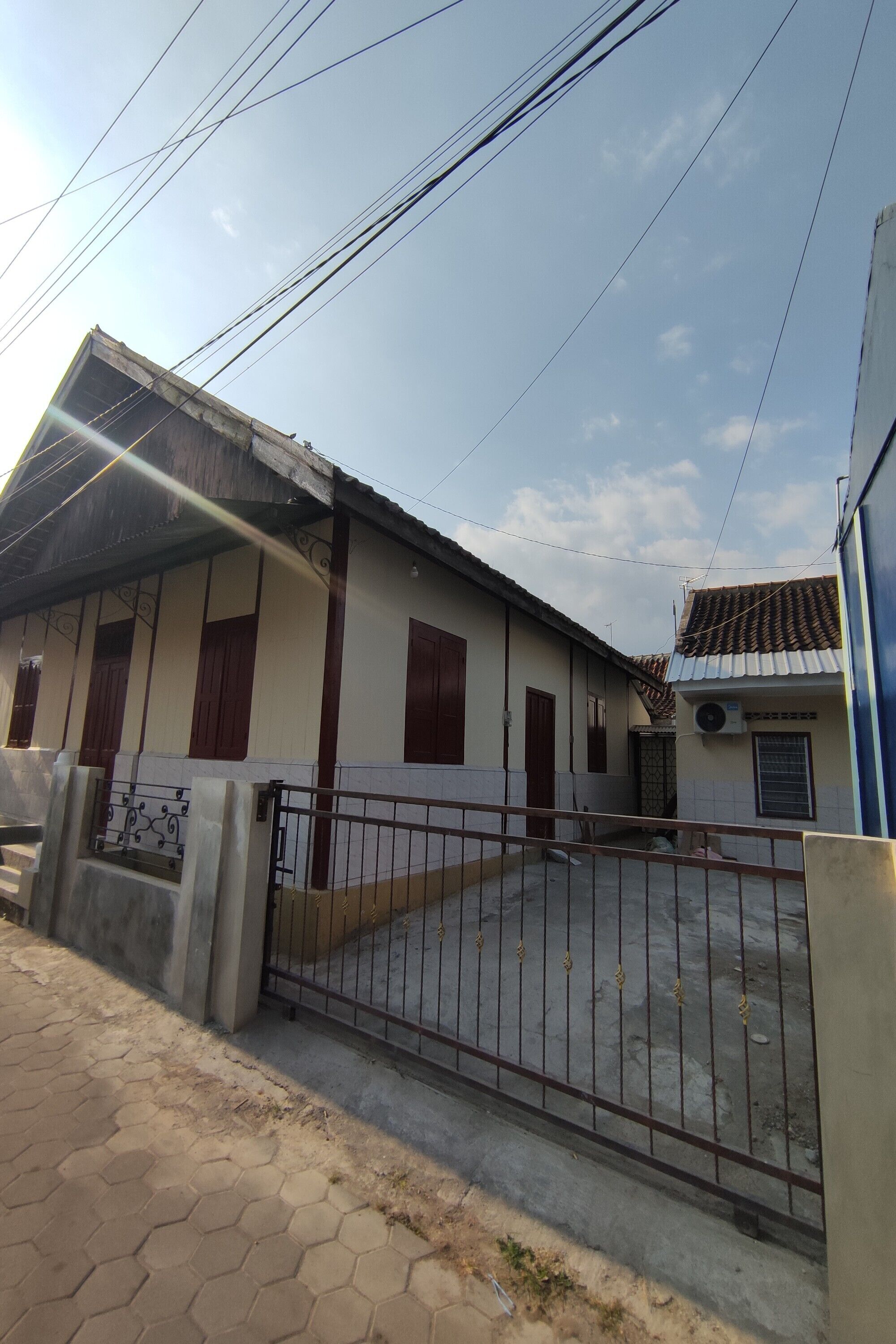 A residential building with a gated entrance, a tiled roof, and a visible air conditioning unit.