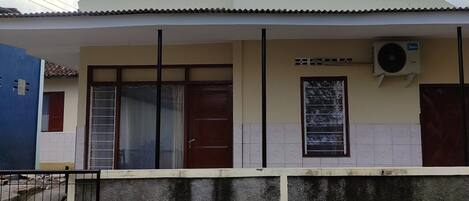 A building with a flat roof, a large window, and an air conditioning unit.