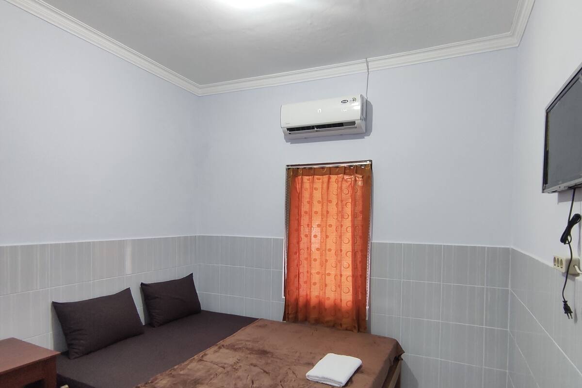 A small, clean room with a bed, a desk, and a TV.