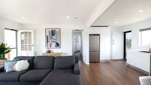 A modern living room with a grey sofa, a small table, and a painting on the wall. - Coastal Breeze (Ulladulla)