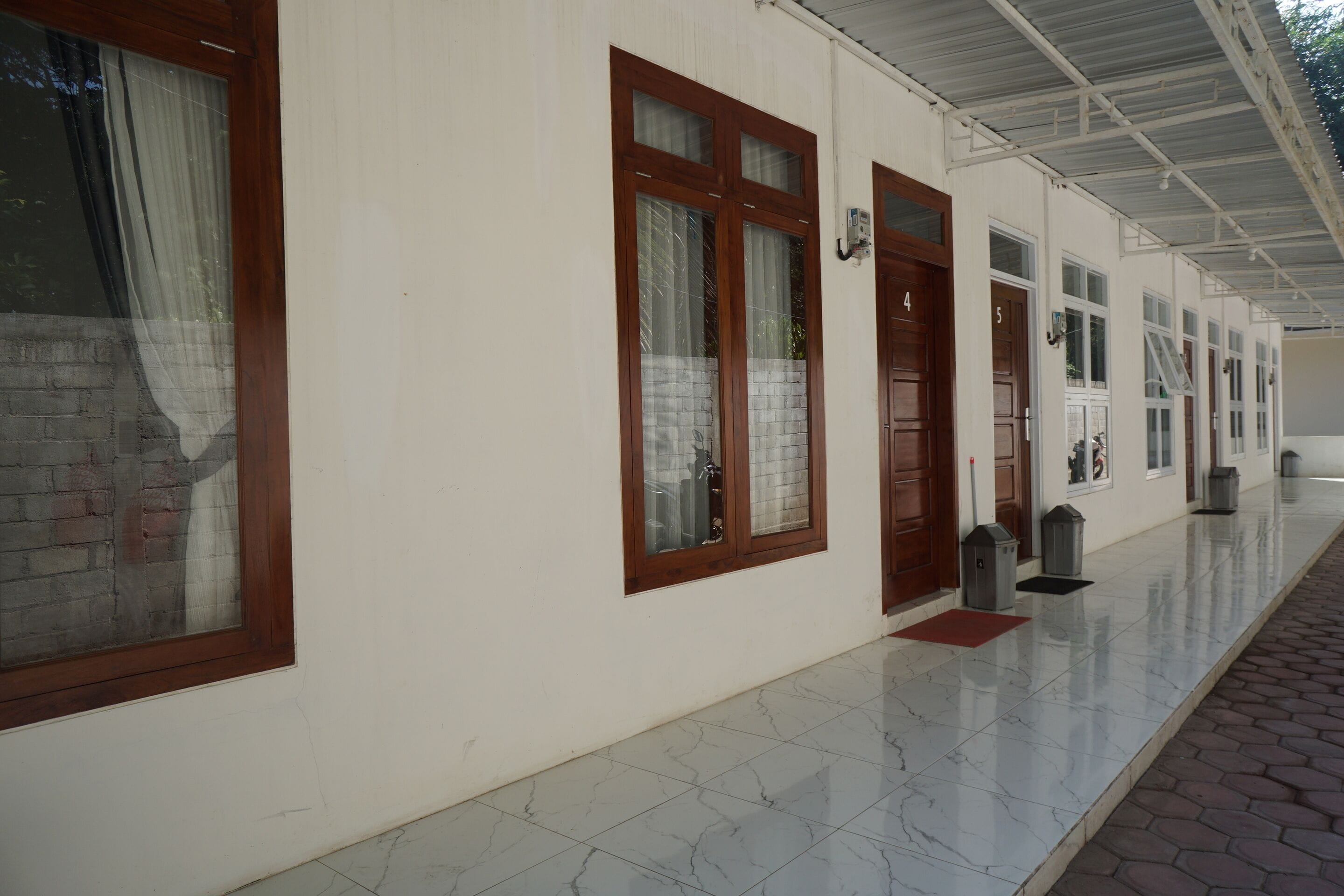 A corridor with doors numbered 4 and 5, a tiled floor, and a brick wall.
