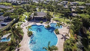 Un quartier résidentiel doté d’une grande piscine, entourée de palmiers et de maisons.