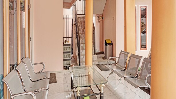 Ein geräumiger Wohnbereich mit Glastisch, Metallstühlen, einer Treppe und einem Mülleimer.