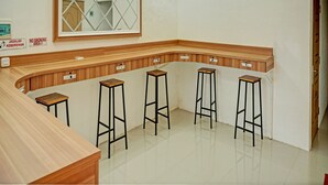 Eine gemütliche Bar mit Holztresen und Hockern, einem Spiegel mit geometrischem Muster sowie Schildern für Raucher- und Nichtraucherbereich.