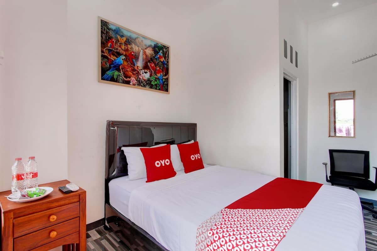 Een hotelkamer met een bed, nachtkastje, schilderij, televisie en een deur.