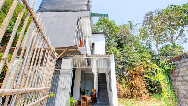 Un bâtiment moderne doté d’un espace extérieur couvert, d’un escalier menant à un étage supérieur et d’une enseigne indiquant le nom du bâtiment.