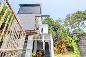 Un bâtiment moderne doté d’un espace extérieur couvert, d’un escalier menant à un étage supérieur et d’une enseigne indiquant le nom du bâtiment.