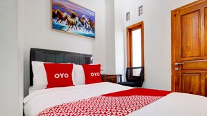 Une chambre d’hôtel avec un lit, un tableau au mur et une porte en bois.