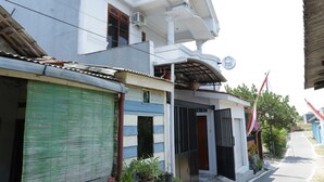 A two-story building with a green shuttered storefront, a balcony, and a sign indicating a business. - SPOT ON 93189 Rumah Berkah Syariah (Blitar)