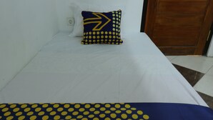 A bed with a white sheet and a blue pillow with yellow polka dots and a large yellow arrow design. - SPOT ON 93189 Rumah Berkah Syariah (Blitar)