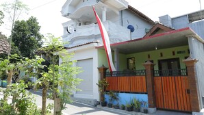A two-story house with a balcony, a garage, and a gated entrance. - SPOT ON 93189 Rumah Berkah Syariah (Blitar)