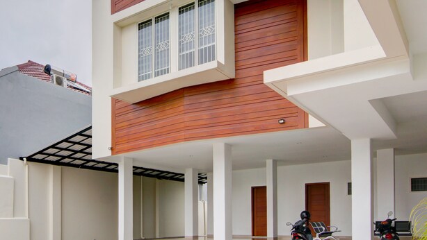 Un edificio moderno con fachada de madera, un espacio al aire libre cubierto y una motocicleta estacionada afuera.