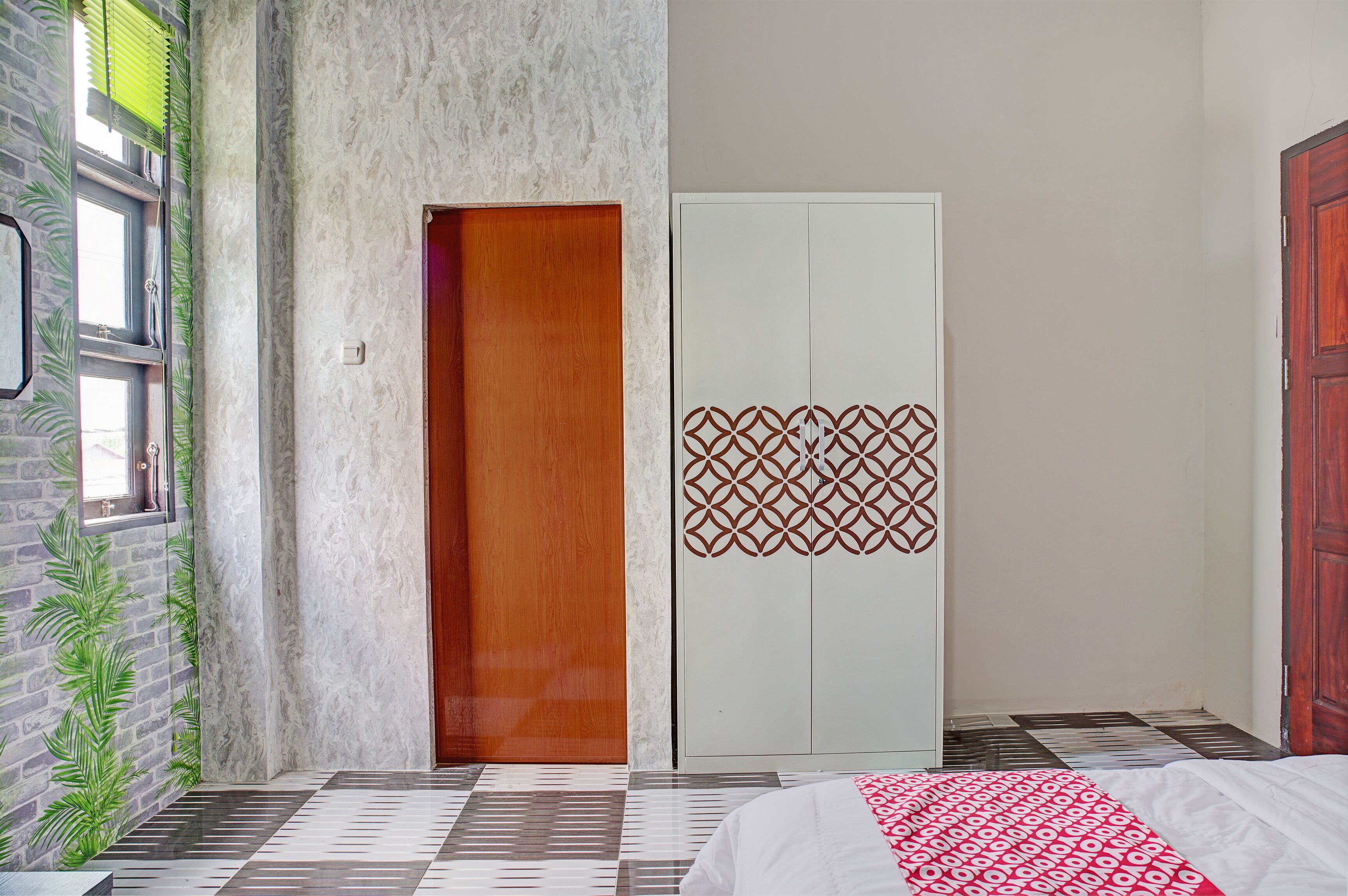 A bedroom with a bed, a wardrobe, a door, and a window with a view of the outside.