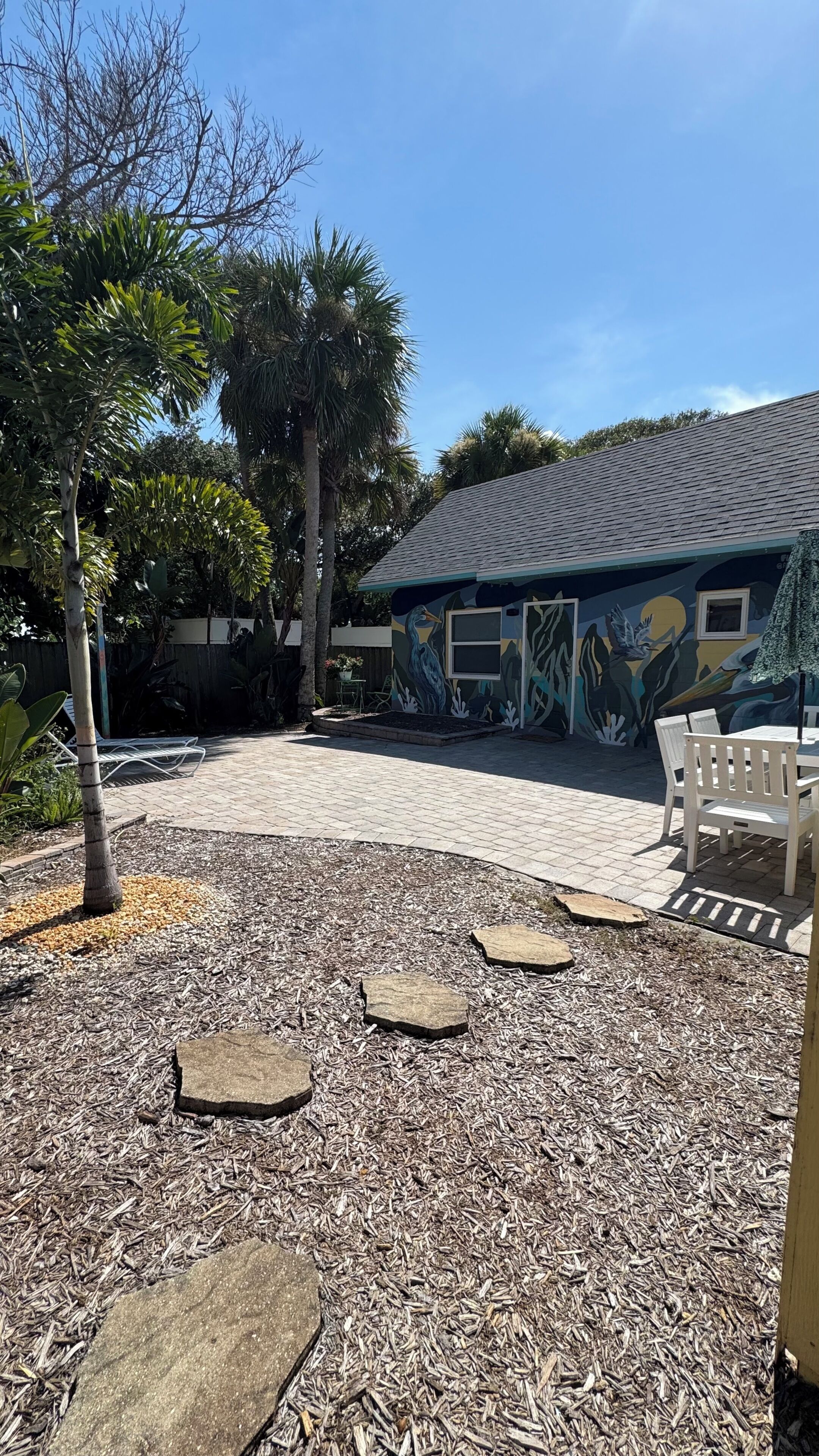 A patio area with a tiled floor, outdoor seating, and a mural on the building.