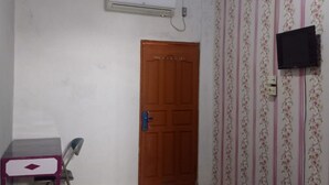 A room with a wooden door, an air conditioning unit, a television mounted on the wall, and a patterned wallpaper. - Hotel O Andesta Guest House SyariahNearAgrowisata Sungai Pinang Agro Nadin (Pekanbaru)