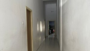 A narrow hallway with white walls and a tiled floor, leading to a room with a visible door at the end. - Hotel O Andesta Guest House SyariahNearAgrowisata Sungai Pinang Agro Nadin (Pekanbaru)