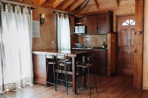 A wooden kitchen with a bar area, a microwave, and a kettle. - Complejo Turístico Valle del Sol Quillón (Quillón)